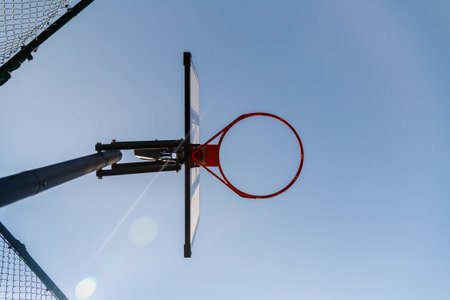 Bottom view of a basketball hoop outdoor. Blue sky as background and copy space. Urban street sport...