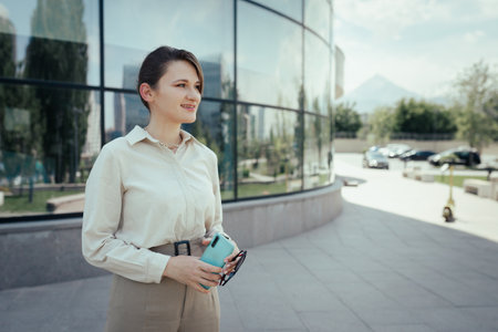 Woman outdoor portrait in business office style with phone in hand in the city streets.の写真素材
