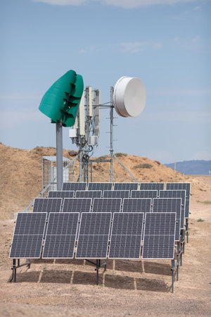 Self-sufficient cell phone tower in the desert with solar panels and a wind turbine.の写真素材
