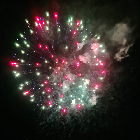 Photo of real fireworks with smoke and green and red sparks on black sky background for overlay blending mode.の写真素材