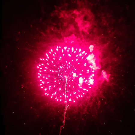 Circle explosion of festive real fireworks with red smoke on black background for overlay blending mode.の写真素材