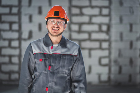 Portrait of a happy laughing bearded worker in overalls at a construction site.の写真素材