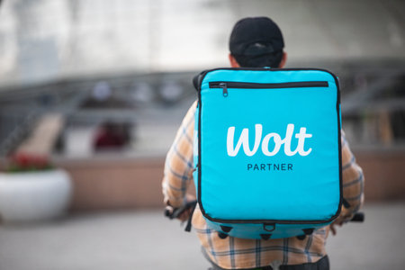 WOLT logo on a blue box by a courier on a bicycle - international food delivery service. Almaty,...