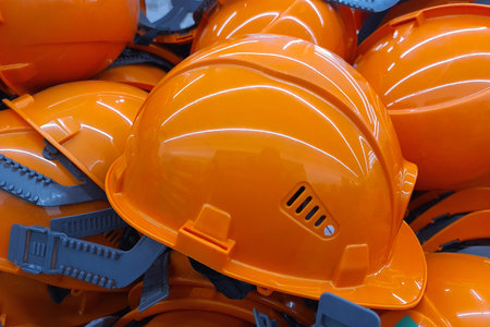 An orange work helmet lies among other similar helmets of general workers.. Construction safety...