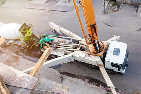 Top-Down Perspective: Concrete Pump Truck Transfers Mixer Truck Load for Floor Pouring at...