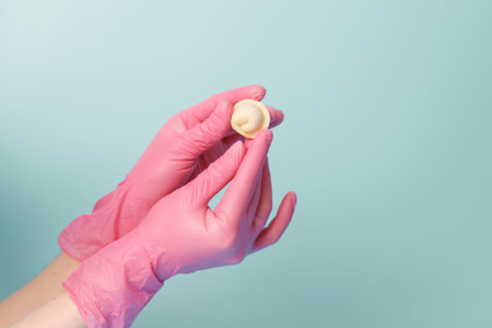 Close-up of a female chefs hands in rubber gloves holding a raw dumpling, concept for the neat...