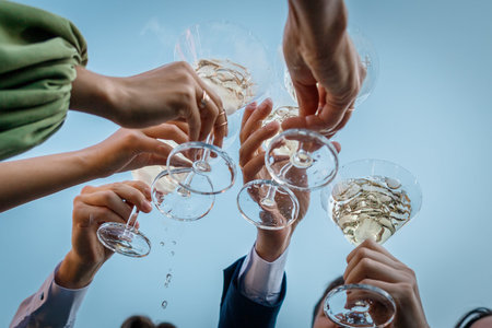 Group of people clinking glasses with martini against the sky during party summer outdoor, closeup.の写真素材