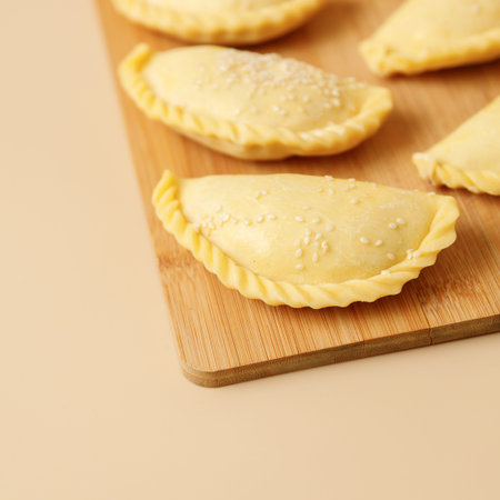 Close-up raw vegetable samsa with sesame on a wooden board . Traditional Indian cuisine, frozen...