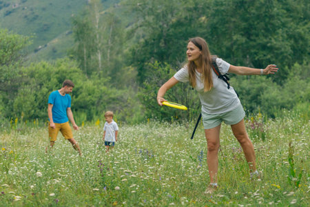 A joyful family is spending a beautiful sunny day playing frisbee in a colorful meadow, surrounded by natureの写真素材