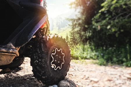 Big aggressive ATV off-road quad bike wheel against a picturesque background of nature calling for...