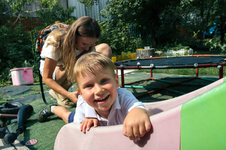 A cheerful young boy is smiling brightly while happily playing at a vibrant playground, surrounded...
