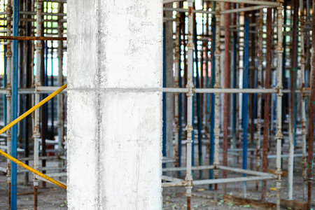Reinforced concrete structural column against the background of scaffolding for pouring concrete...