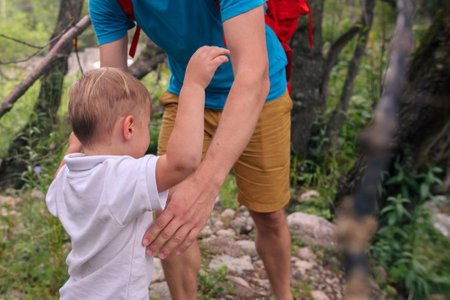 A joyful moment showcasing a caring father who is helping his child successfully navigate a beautiful forest trailの写真素材
