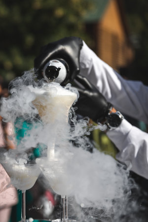 Mobile catering bartender pours alcohol in glasses with martini pyramid with smoke steam, foggy party bar summer outdoor.の写真素材