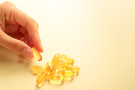 Hand takes one capsule with the micronutrient omega 3 from a pile of these capsules, copy space.の写真素材