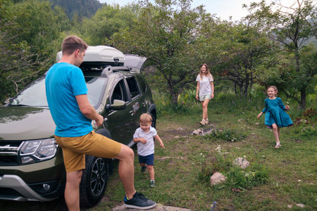 A joyful family happily enjoying quality time together outdoors, traveling in their car amidst beautiful natureの写真素材