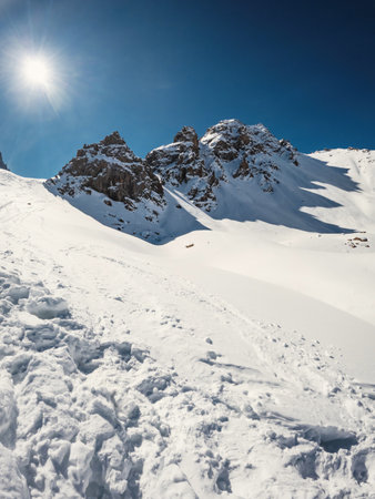 3 scenic rocky peaks cast shadows from the cold winter sun on a snow-capped high mountain pass, copy space, vertical.の写真素材