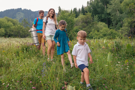 A happy family enjoys a delightful hike together through a vibrant, lush green meadow, embracing natures beautyの写真素材