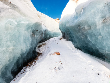 An incredible winter landscape awaits on the journey to the Bogdanovich Glacier in the Almaty Mountains of Kazakhstan. Trail winds through a blue ice corridor, adorned with mountain stones.の写真素材