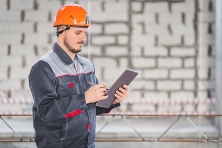 Caucasian construction worker with digital tablet and stylus in his hand, copy space.の写真素材