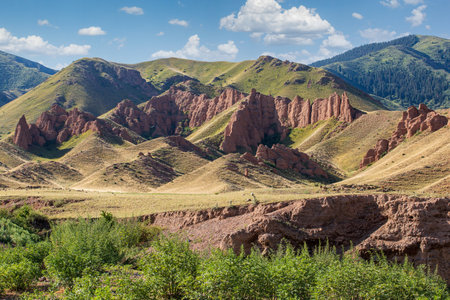Stunning red rock formations majestically rise amidst the lush green mountains, showcasing natures incredible beauty of Kazakhstan, Almaty region.の写真素材