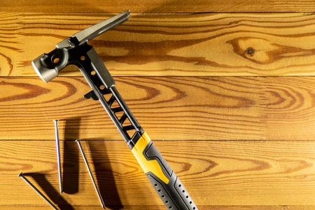 A claw hammer accompanied by assorted nails, placed on a rustic wooden table surface, copy space, top viewの写真素材