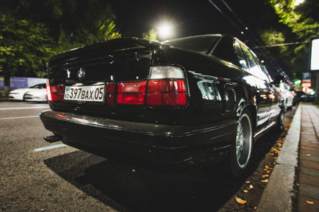 Back view showing the iconic taillights and spoiler of a black BMW E34 on an urban street. Almaty, Kazakhstan - October 04, 2024のeditorial素材