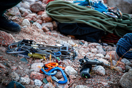 Detail shot of climbing equipment including ropes, carabiners, nuts, and camming devices laid out on...