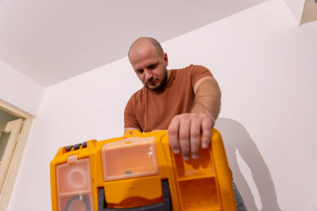 Close up shot of a man opening a bright yellow plastic toolbox to select tools for a home repair...