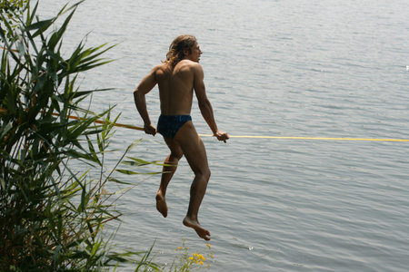 skackline above the water. The guy sitting on slacklineの写真素材