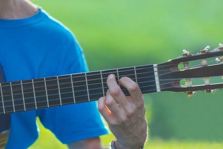 Man's hand playing acoustic guitar, close up