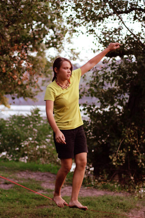 girl walks on Slackline on the background of the river and the trees