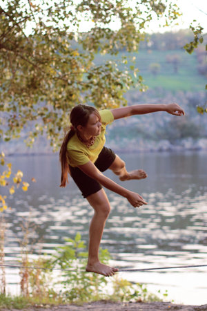 girl walks on Slacklining on the background of the river and the trees