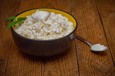 A plate with cottage cheese and a spoon on a wooden table.の写真素材