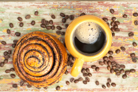 Strong dark cup of coffee with kanelbule on wooden background. Coffee beans. Close-up.Top view.の写真素材