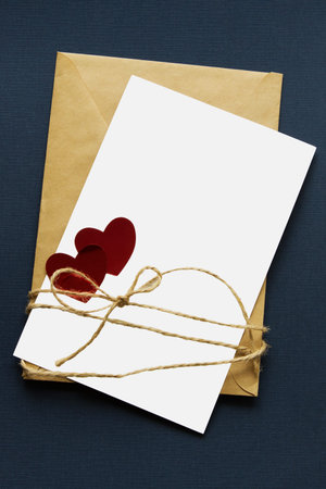 Isolated on white blank with two red hearts lies on a craft paper envelope that tied with a vintage...