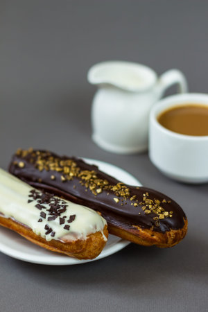 Two eclairs near a cup of coffee