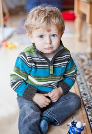 Adorable toddler with blue eyes and blond hair indoorの写真素材
