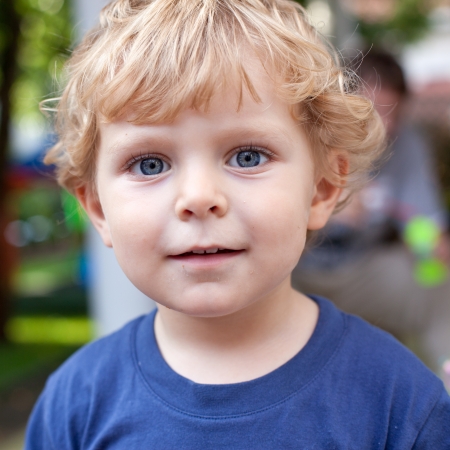 Portrait of little toddler boy with blond hairs and blue eyes in summerの写真素材