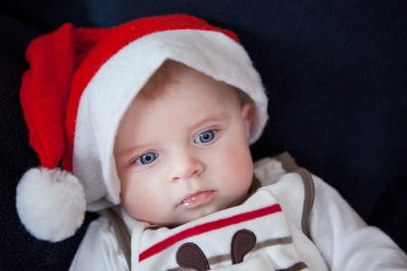 Little baby boy in red Christmas cap on dark backgroundの写真素材