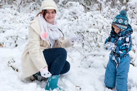 Young mother and little toddler boy having fun with snow outdoors on beautiful winter dayの写真素材