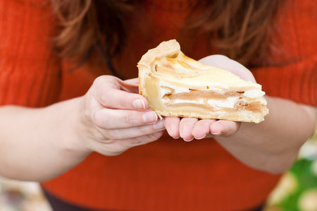 Fresh baked apple pie on wooden cutting board holding by hand of a womanの写真素材