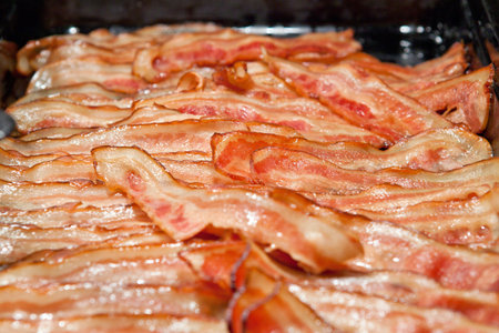 Slices of smoked grilled crusty bacon on big tray in hotel restaurant