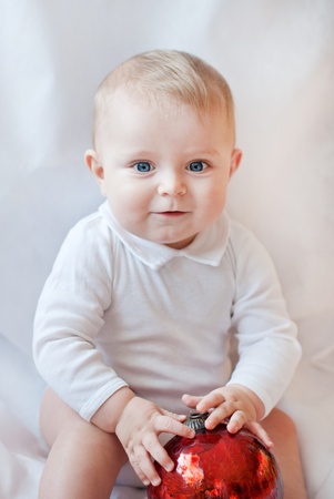 Cute baby toddler playing with Christmas tree balls on white backgroundの写真素材
