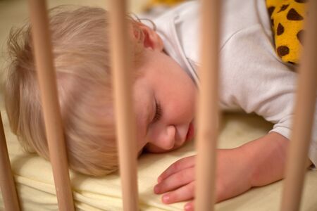 Beautiful toddler boy sleeping in his bedの写真素材