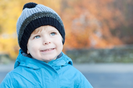 Beautiful toddler boy in blue clothes dreaming on sunny winter dayの写真素材
