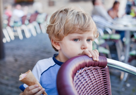 Little toddler boy eating ice cream in cone in summerの写真素材