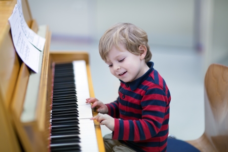 Two years old happy toddler boy playing pianoの写真素材