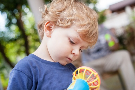 Little sweet toddler boy playing with toy in summer garden outdoorsの写真素材