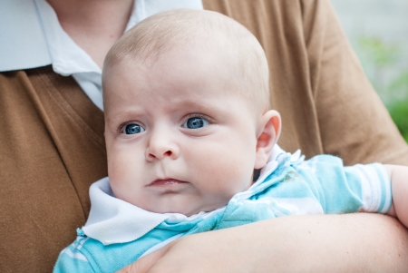 Little baby boy with blue eyes on father's arm in summerの写真素材